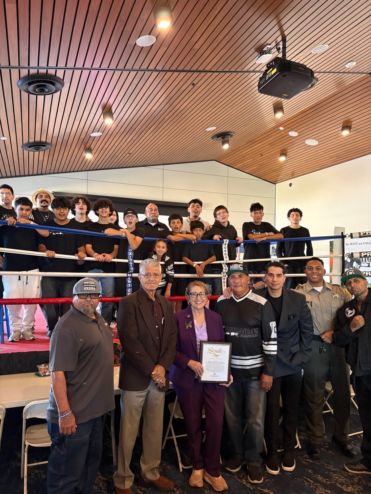 Group photo at the ring with a California State Senate certificate of recognition for the 9th Annual Neighborhood Champions Veterans Boxing Show