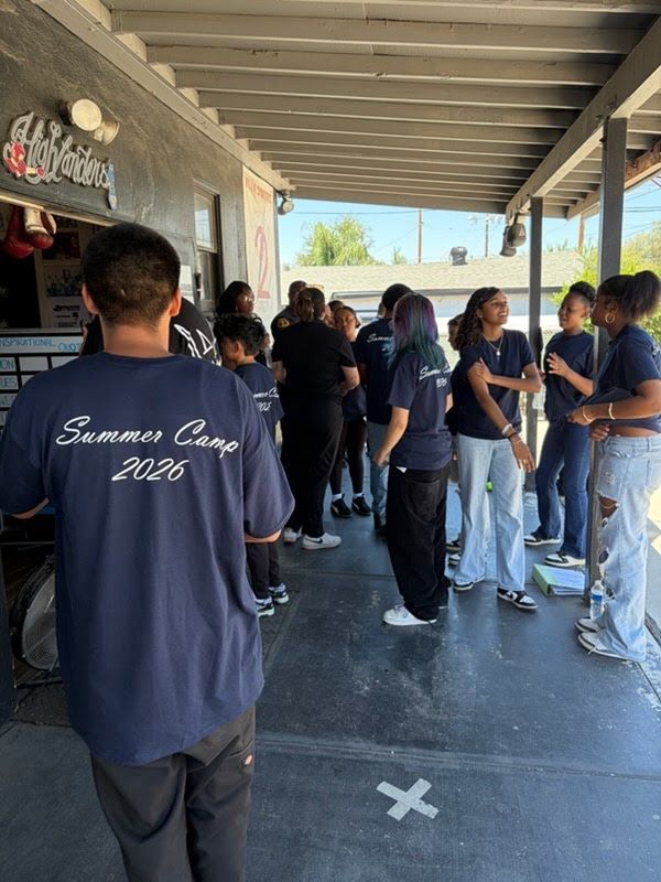 HBC youth wearing their navy Summer Camp 2026 shirts, gathered together at the Highlanders Boxing Club gym
